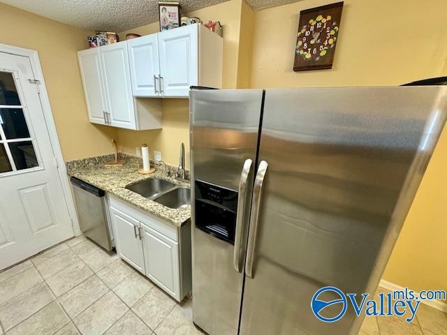 kitchen featuring light stone counters, sink, a textured ceiling, white cabinetry, and stainless steel appliances