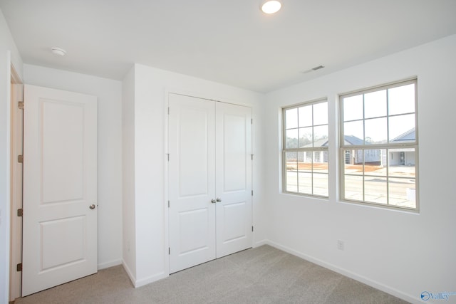 unfurnished bedroom with a closet and light colored carpet