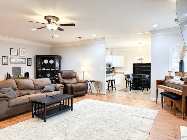 living area with recessed lighting, ceiling fan with notable chandelier, light wood-style floors, and baseboards