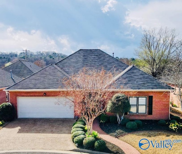 single story home with a garage, brick siding, driveway, and a shingled roof