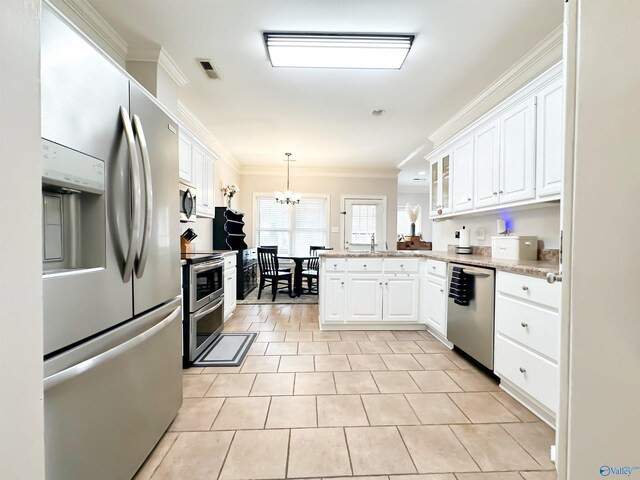 kitchen with visible vents, a peninsula, white cabinets, appliances with stainless steel finishes, and a chandelier
