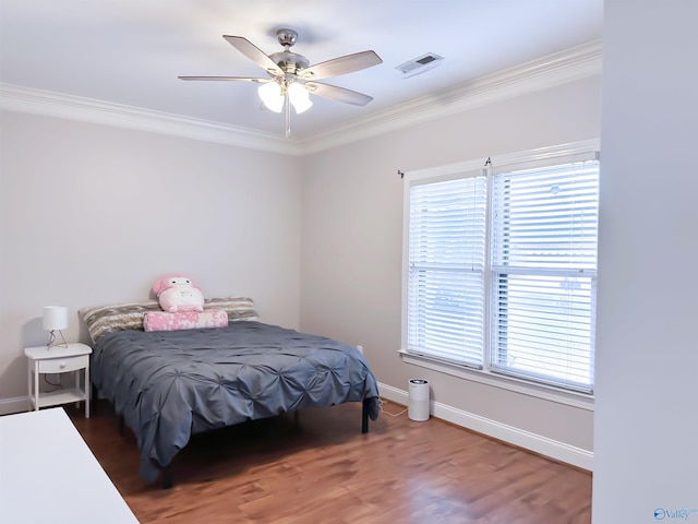 bedroom with visible vents, a ceiling fan, wood finished floors, crown molding, and baseboards