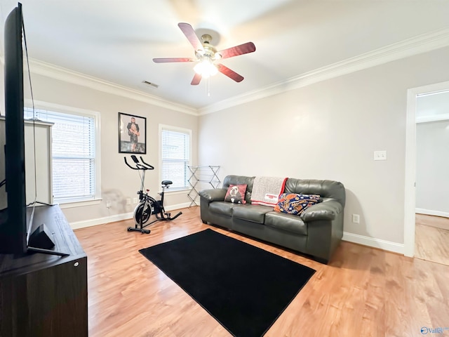 living area with visible vents, crown molding, baseboards, wood finished floors, and a ceiling fan