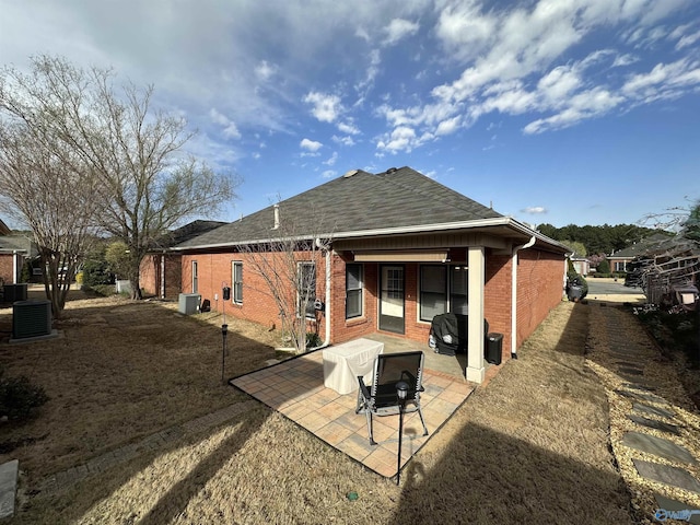 rear view of property featuring brick siding, central AC, a shingled roof, and a patio area