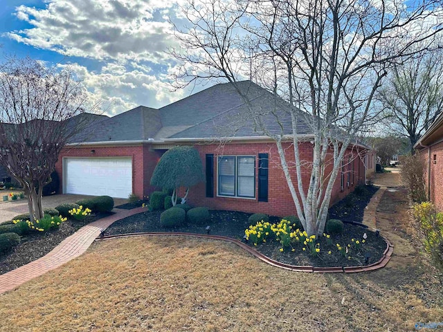 single story home with brick siding, an attached garage, a shingled roof, and a front yard
