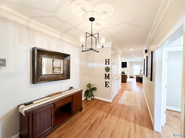 hallway with a notable chandelier, ornamental molding, recessed lighting, light wood finished floors, and baseboards