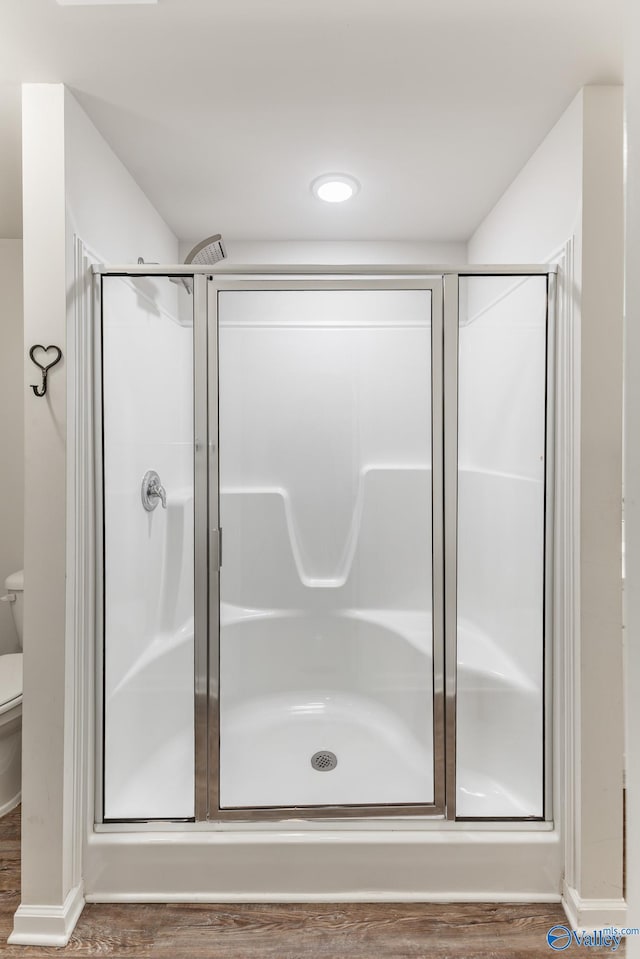 bathroom featuring wood-type flooring, toilet, and walk in shower