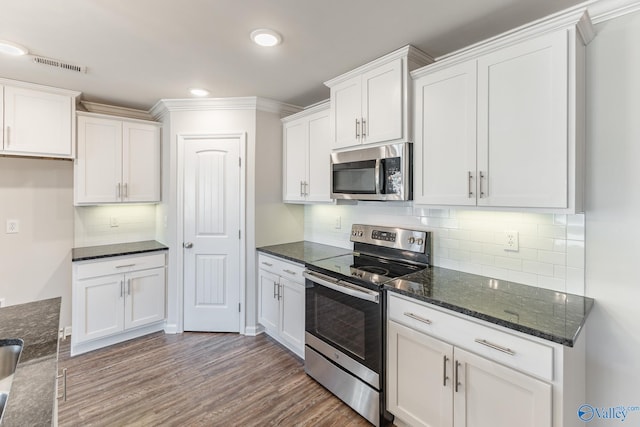 kitchen with decorative backsplash, stainless steel appliances, wood-type flooring, dark stone countertops, and white cabinetry