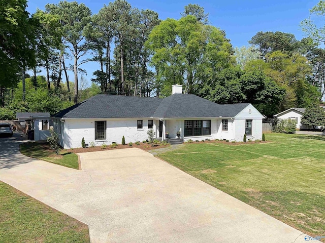 ranch-style home featuring a chimney, a front lawn, and driveway