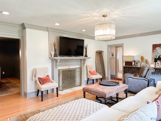 living area with wood finished floors, an inviting chandelier, a fireplace, baseboards, and recessed lighting