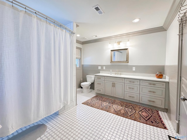 bathroom featuring wainscoting, toilet, crown molding, and tile walls