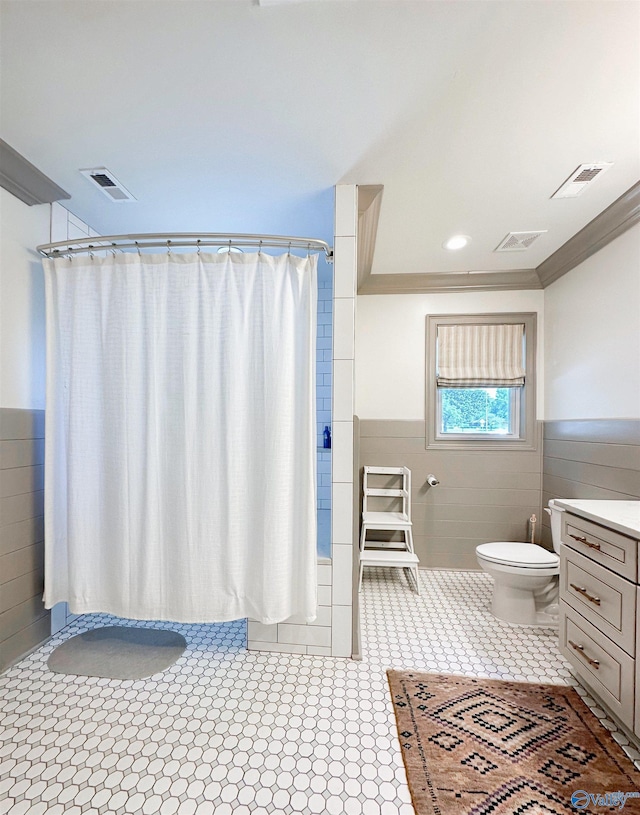 bathroom with tile walls, visible vents, and wainscoting