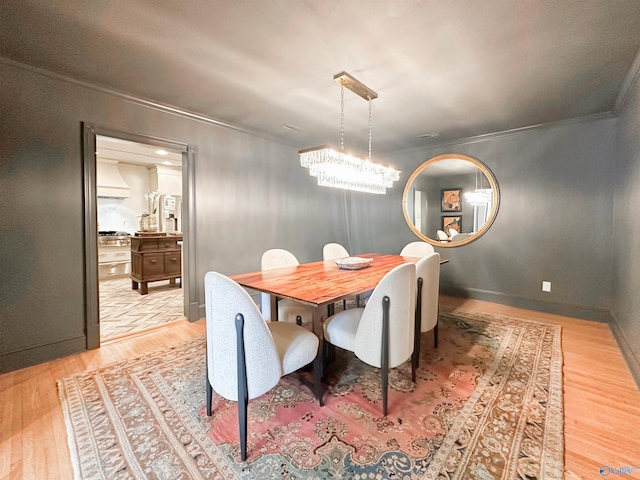 dining area with baseboards, wood finished floors, a notable chandelier, and crown molding