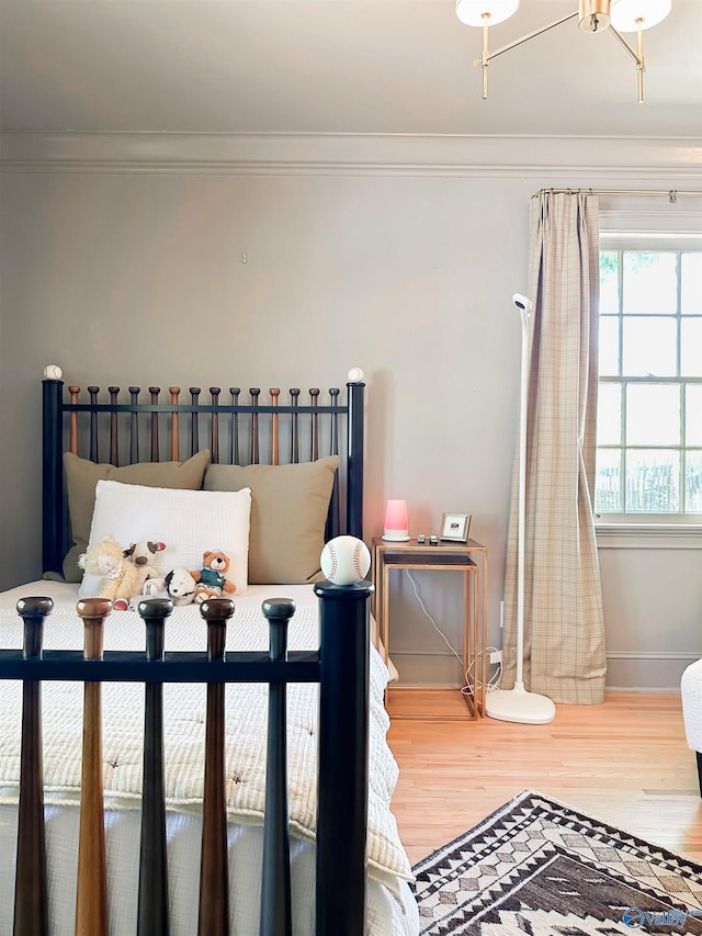 bedroom with baseboards, ornamental molding, and wood finished floors