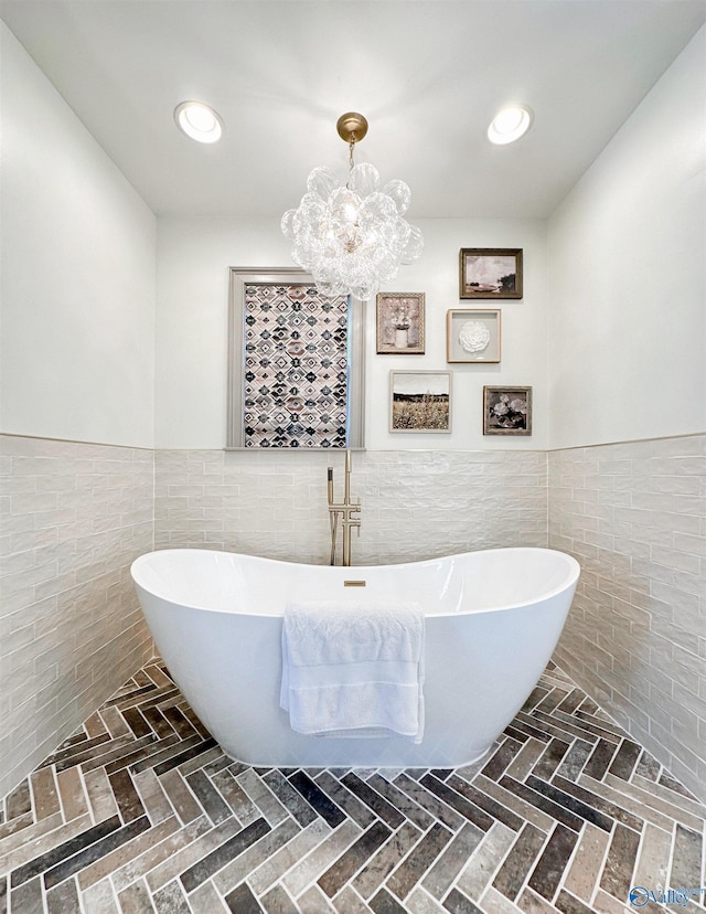 bathroom with wainscoting, an inviting chandelier, and tile walls