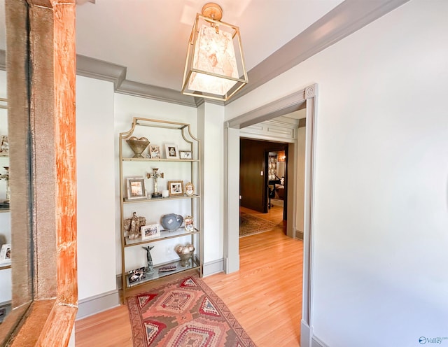 hall with light wood-style flooring and crown molding