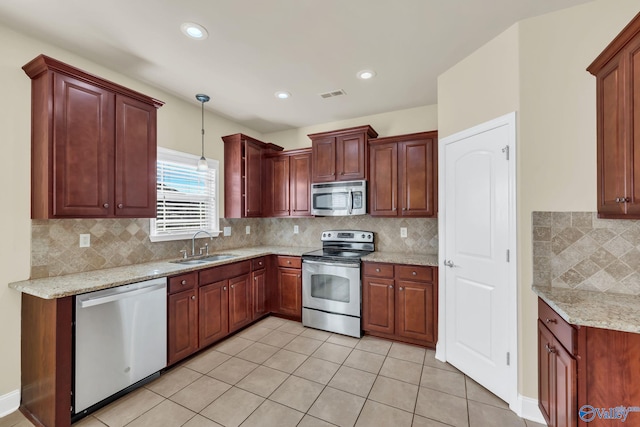 kitchen with appliances with stainless steel finishes, hanging light fixtures, sink, and decorative backsplash