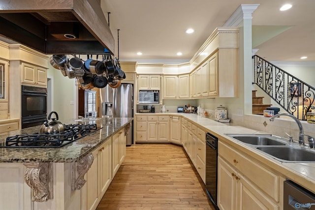 kitchen featuring sink, black appliances, light hardwood / wood-style floors, light stone countertops, and a kitchen bar