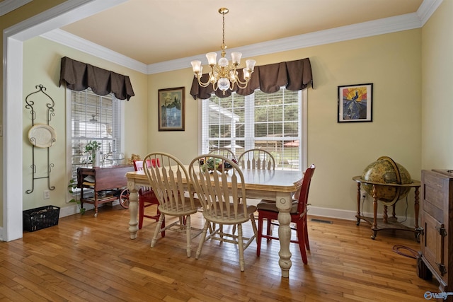 dining space featuring wood-type flooring, crown molding, and an inviting chandelier