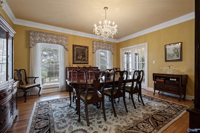 dining area with hardwood / wood-style flooring, crown molding, and a chandelier