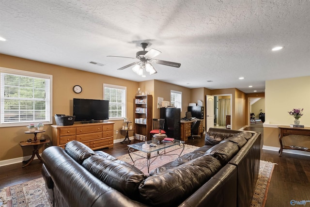 living room featuring ceiling fan, a textured ceiling, dark hardwood / wood-style floors, and a healthy amount of sunlight