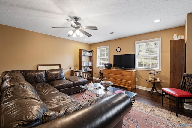 living room featuring ceiling fan, dark hardwood / wood-style floors, and a textured ceiling