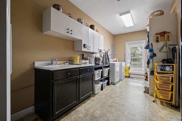 kitchen with white cabinetry, sink, a textured ceiling, and washer and clothes dryer