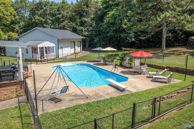 view of swimming pool featuring a patio, a diving board, and a yard