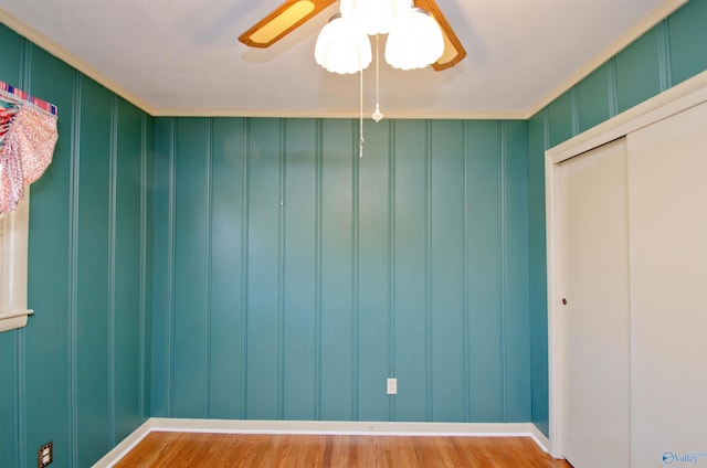 unfurnished room with a ceiling fan, a decorative wall, and wood finished floors