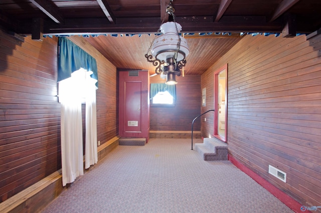 hall featuring carpet floors, beam ceiling, wood ceiling, and wooden walls