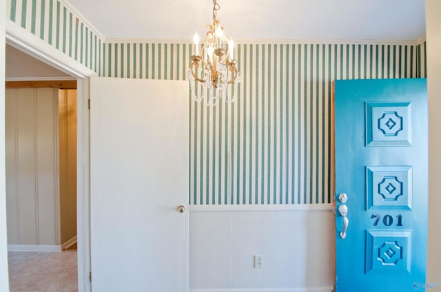 interior space with wallpapered walls, a chandelier, and a wainscoted wall