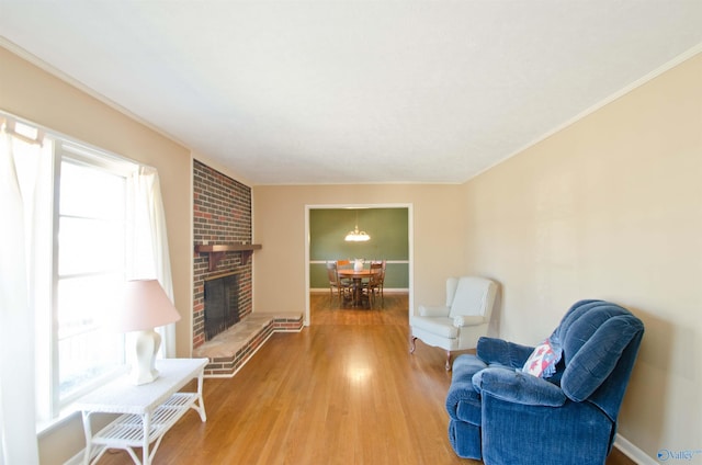 living area with baseboards, plenty of natural light, wood finished floors, and a brick fireplace