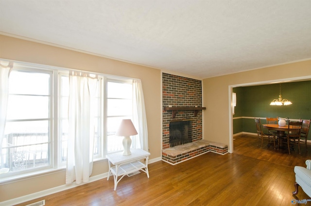 living room with a fireplace, wood finished floors, an inviting chandelier, and baseboards