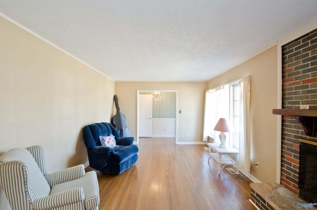 sitting room featuring a fireplace, ornamental molding, wood finished floors, a chandelier, and baseboards