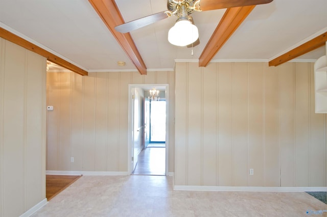 empty room featuring beamed ceiling, a ceiling fan, and baseboards