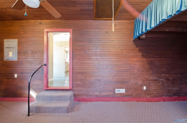 interior space featuring a ceiling fan, visible vents, carpet flooring, and wooden walls