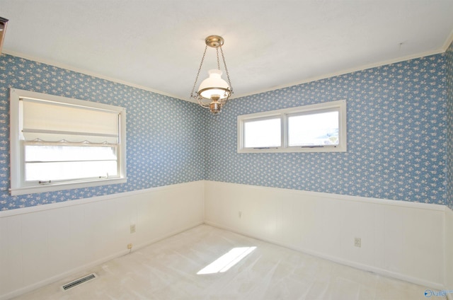 empty room with wallpapered walls, visible vents, ornamental molding, and wainscoting