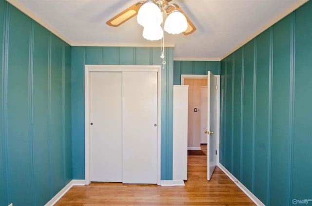 unfurnished bedroom with crown molding, a closet, a decorative wall, and wood finished floors