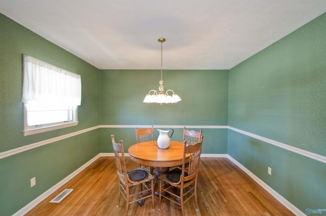 dining area with baseboards, visible vents, a chandelier, and wood finished floors