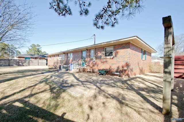 back of property with crawl space, fence, a lawn, and brick siding