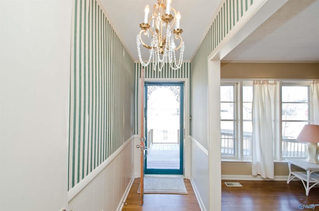 doorway with a chandelier, a healthy amount of sunlight, visible vents, and wood finished floors