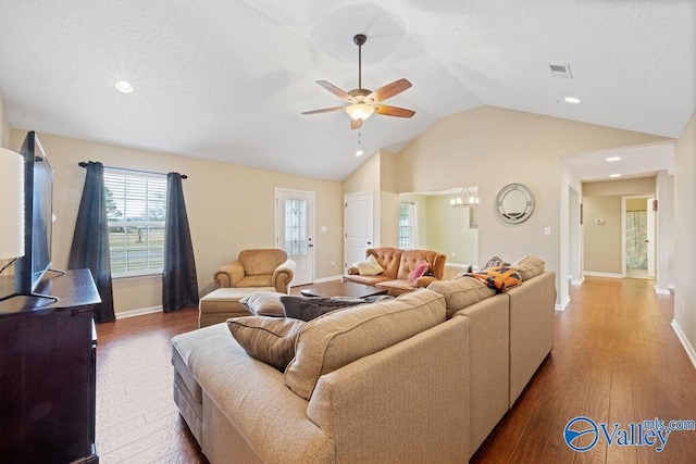 living area featuring lofted ceiling, hardwood / wood-style floors, visible vents, and a ceiling fan