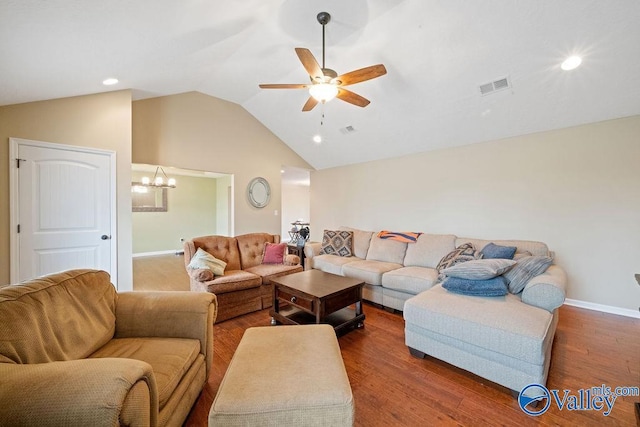 living room with ceiling fan with notable chandelier, wood finished floors, visible vents, baseboards, and vaulted ceiling