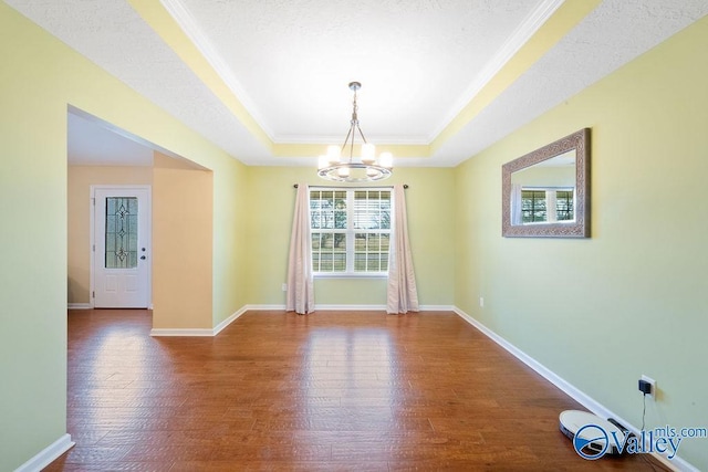 unfurnished room with an inviting chandelier, baseboards, a tray ceiling, and wood finished floors