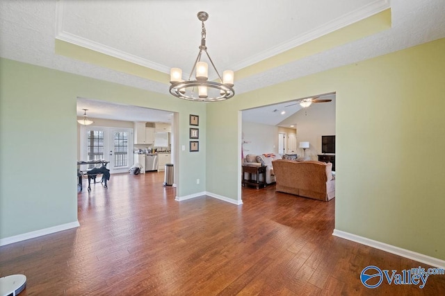 dining space with a raised ceiling, crown molding, baseboards, and hardwood / wood-style flooring