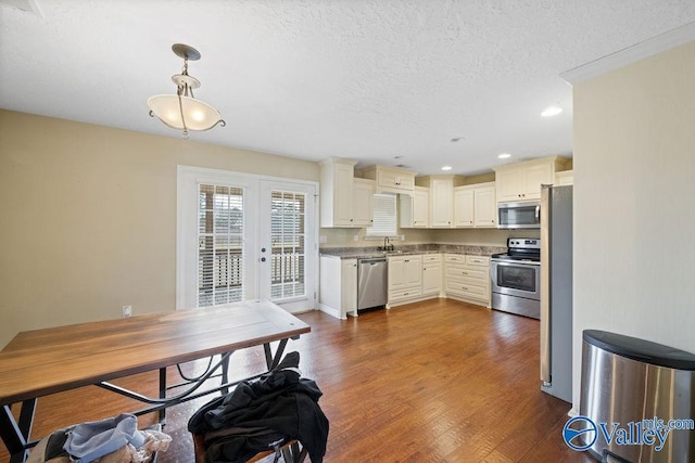 kitchen with pendant lighting, french doors, appliances with stainless steel finishes, dark wood-type flooring, and a textured ceiling