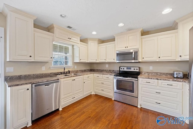 kitchen with recessed lighting, stainless steel appliances, a sink, visible vents, and dark wood-style floors