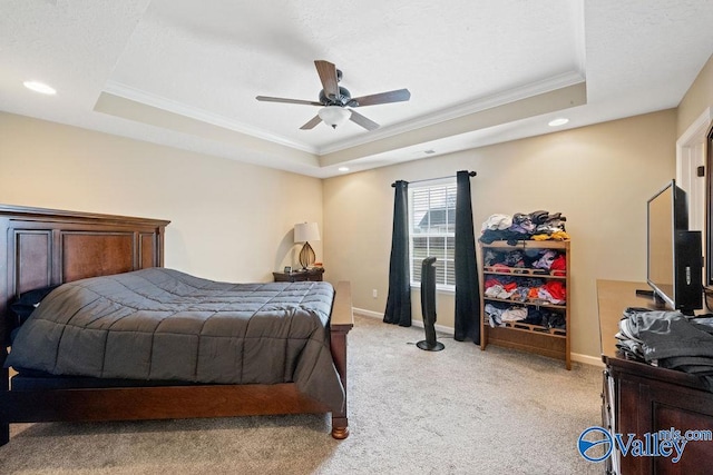 bedroom featuring a tray ceiling, crown molding, light colored carpet, ceiling fan, and baseboards