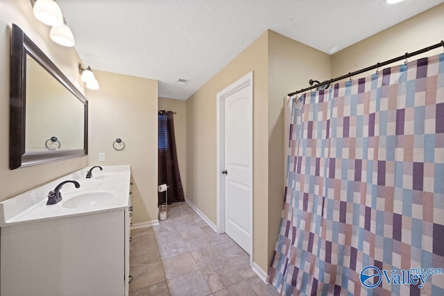 bathroom featuring visible vents, a sink, baseboards, and double vanity