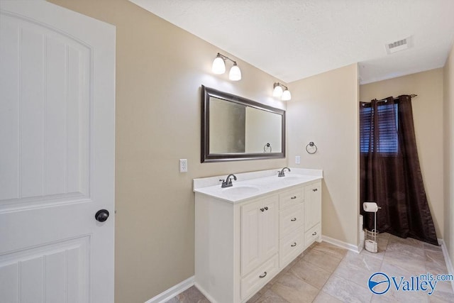 full bath featuring double vanity, baseboards, visible vents, and a sink